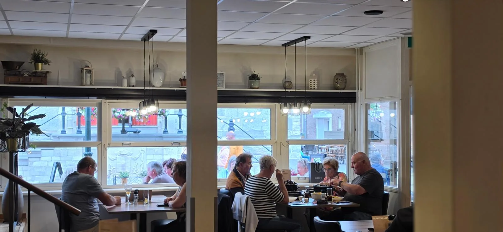 Gasten aan tafel bij het raam