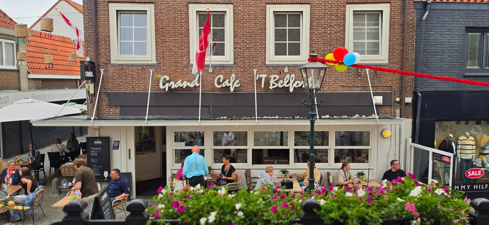 De gevel met vlaggen en bloembakken langs het terras